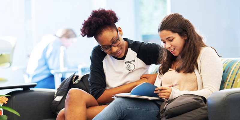 Two students reading a notepad together on the student success center