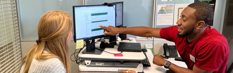 Academic advisor pointing to something on computer screen while student watches