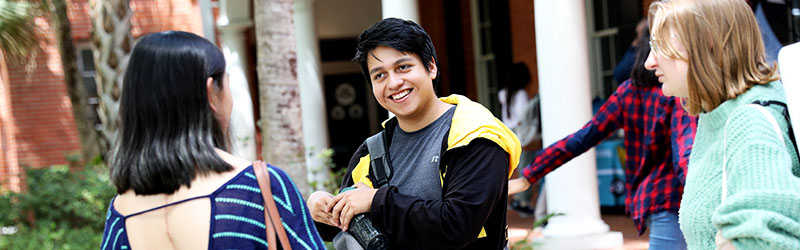 three students talking and smiling on campus