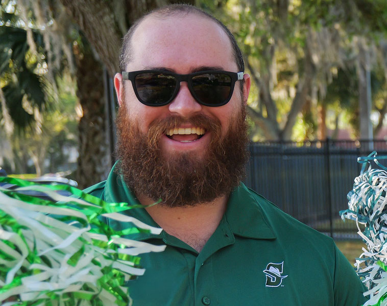 admissions recruiter smiling and holding a pom pom