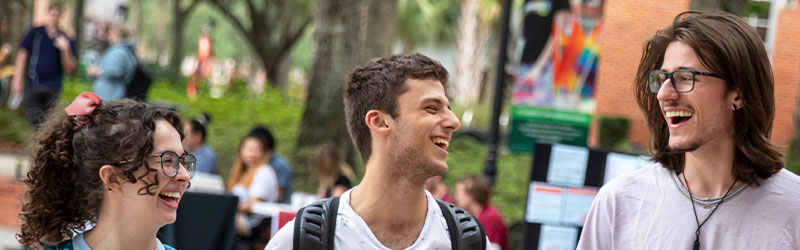 one girl and two guys laughing together outside