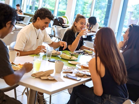 students sitting on table laughing and eating