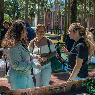 A mother and daughter talking with a faculty member in the Palm Court