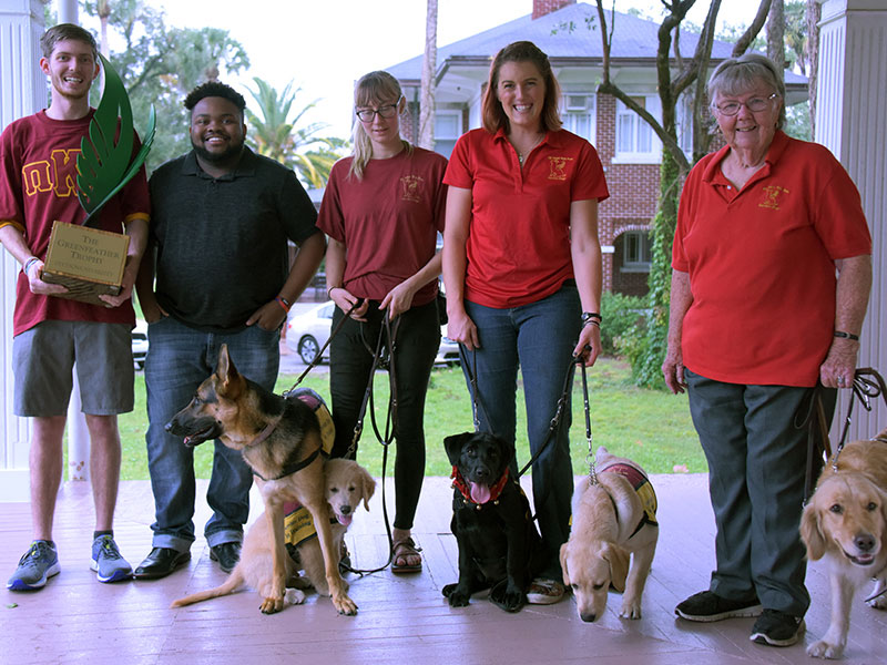 Students posing with their service dogs after winning The Greenfeather Trophy