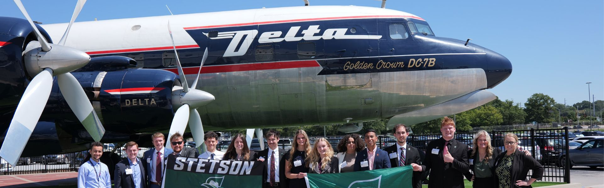 students in front of airplane during delta company trip