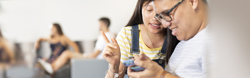 Two people talking while looking at a phone