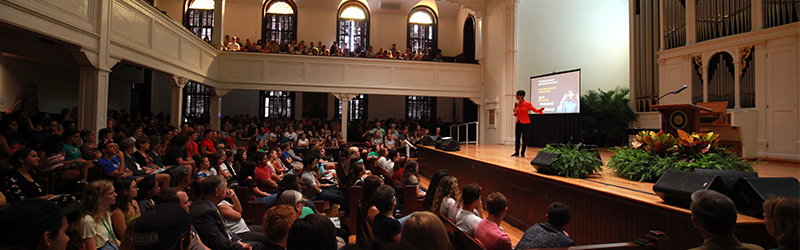 An auditorium full of people watching a speaker in Lee Chapel.
