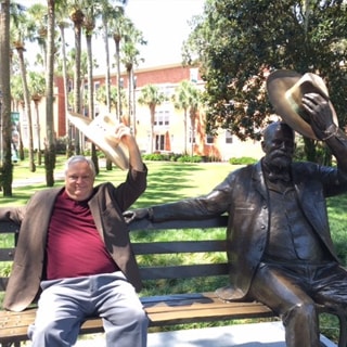 Dr. Charles Gillespie sitting beside the John B statue
