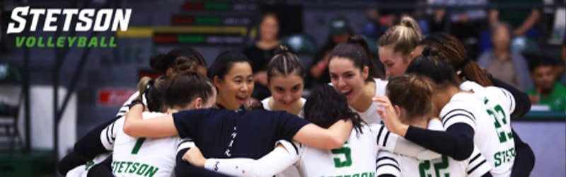 Women's Indoor Volleyball team group hugging before game