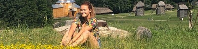 student sitting in a field in Ukraine