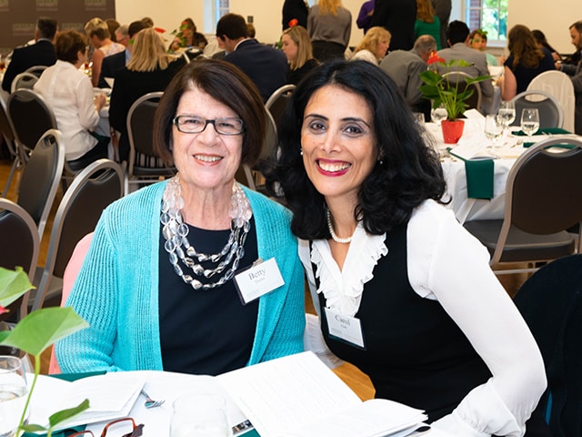 an image of 2 donors at table smiling