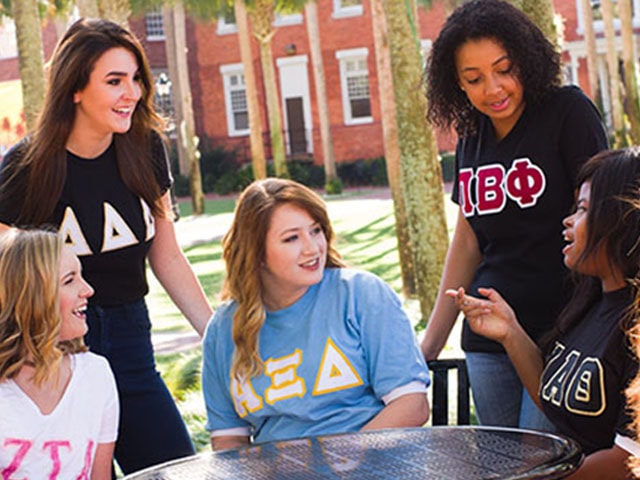 A group of students around an outside table talking