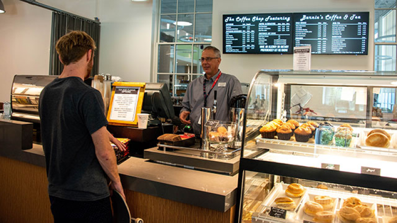 student purchasing at cash register with cashier