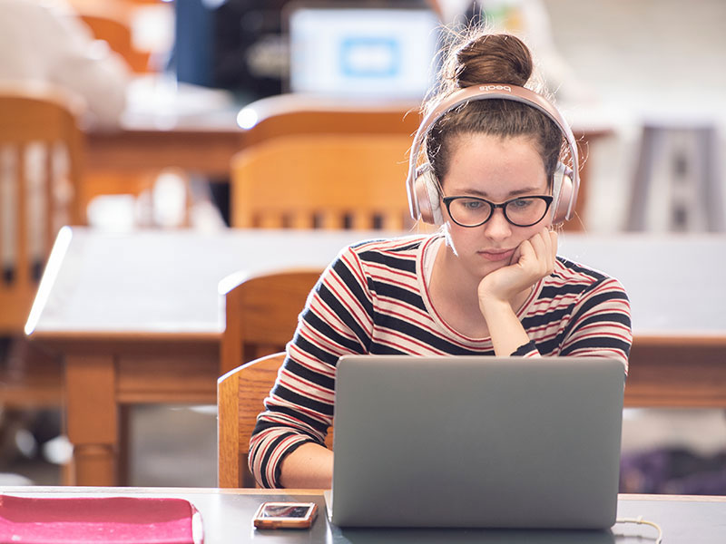 a student with headphones working on their laptop