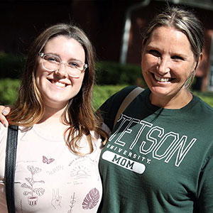 A parent and student poising together on campus