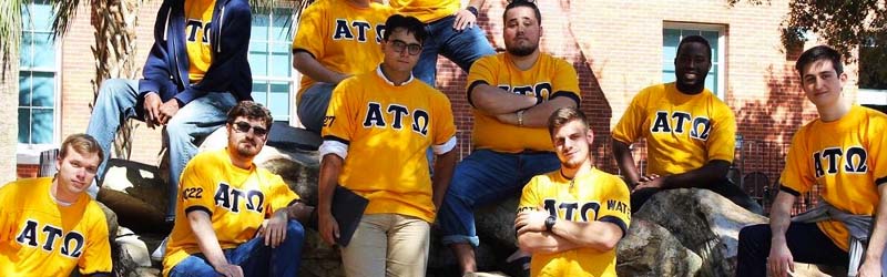 group of students from fraternity sitting on rocks 