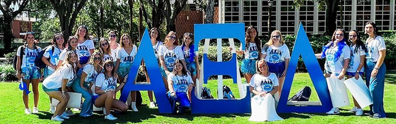 students from sorority posing and smiling together holding their symbol signs