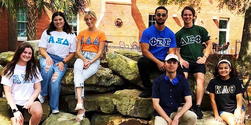 students from different greek organizations sitting on rocks together