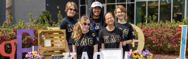 students from sorority posing and smiling together at their table