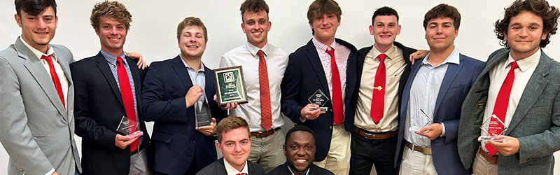 students from fraternity posing and smiling together with trophies