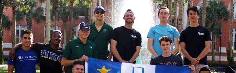 students from fraternity posing together holding their flag