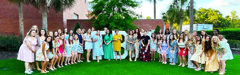 students from sorority posing and smiling together with their symbol signs