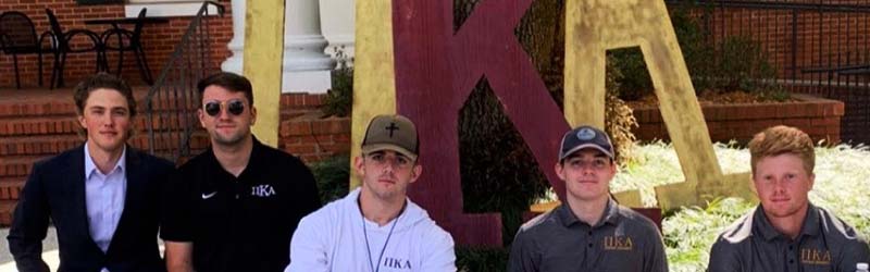 students from fraternity posing together behind their sign