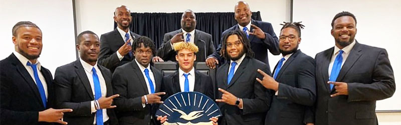 students from fraternity posing and smiling together making their hand signs