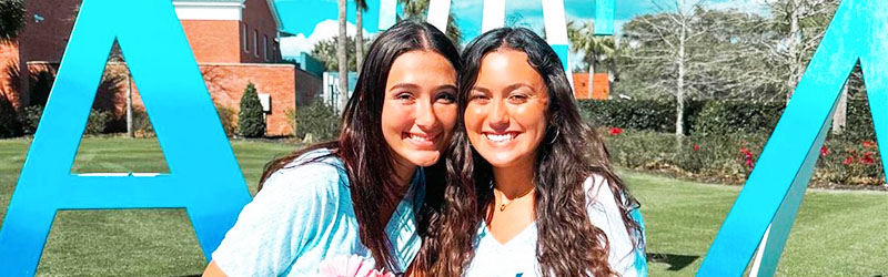 two girls from a sorority smiling together on campus