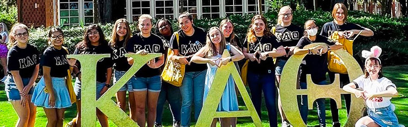 students from sorority posing and smiling together holding their symbol signs