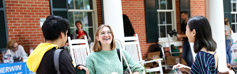 three smiling students outside talking together