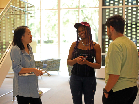 two students talking with one professor asking questions