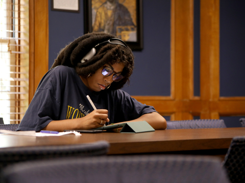 student studying with headphones on with their ipad