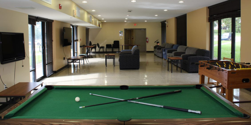 Lounge of a house, with a billiard table, sofas, chairs and TVs