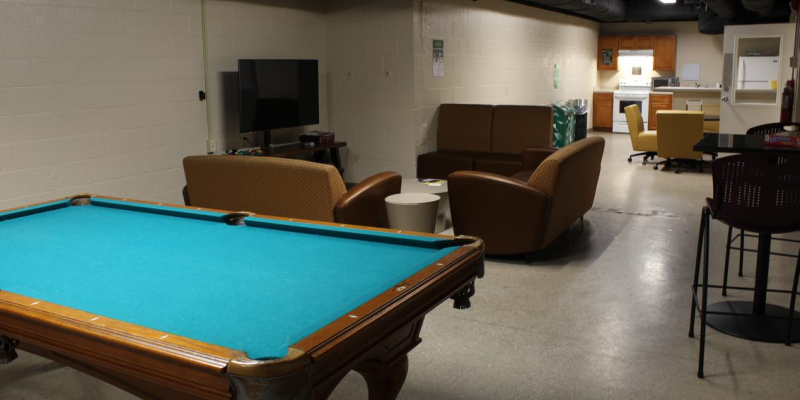 Basement kitchen of Carson and Hollis Halls, with a TV, sofas, billiard table, oven and stove