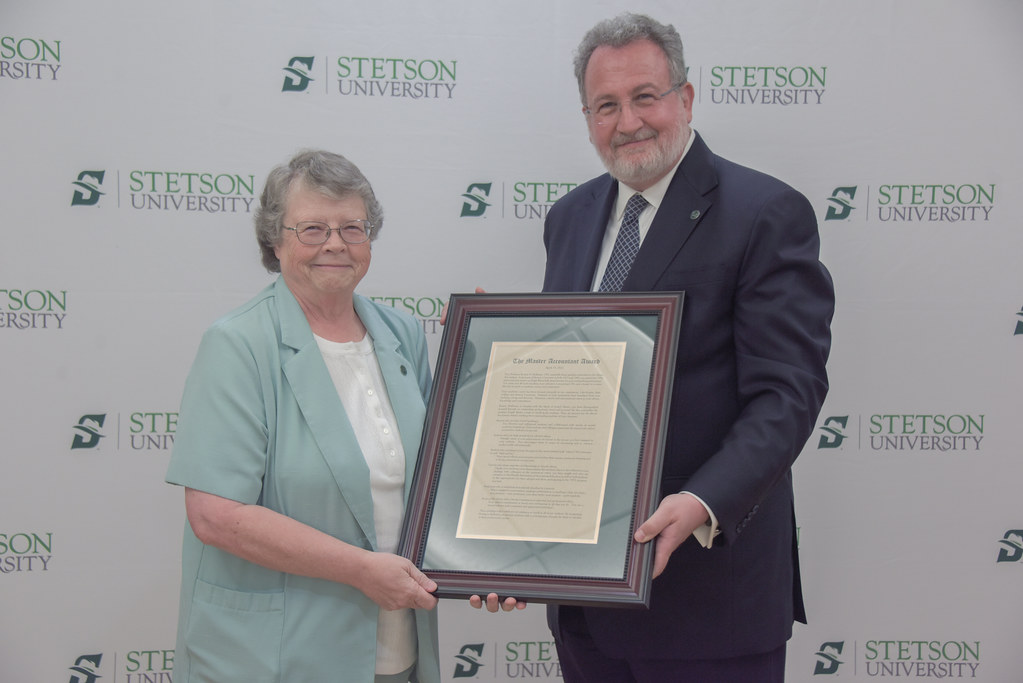 A woman and a man proudly display a framed award at a Stetson University event.