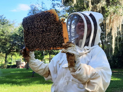 student with protective gear holding bea hive