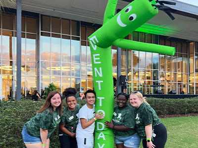 students smiling outside with inflatable guy for an event