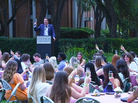 students raising their glasses for a toast with the president during senior toast