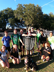students from teh disc golf team smiling outside with a dog 