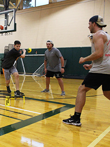 three students playing spikeball together