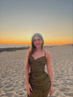 Nina is wearing a green dress on a beach.