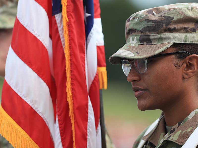 student in uniform next to american flag