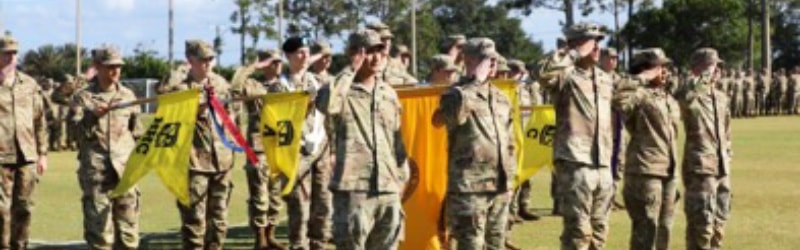 rotc cadets holding falgs and saluting outside