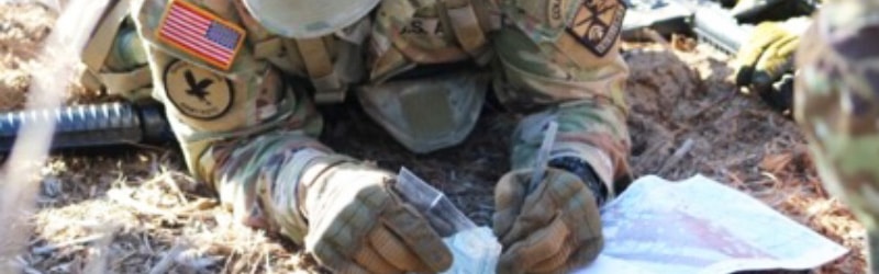 student on uniform leaning down to write while on the field