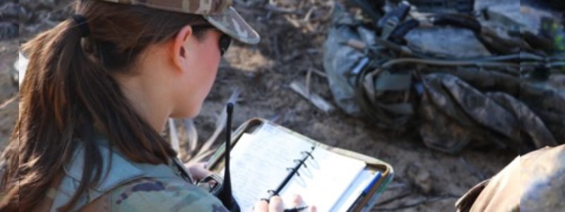 girl from rotc writing on notebook while on the field