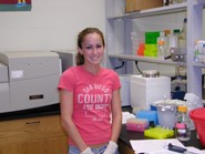 A student smiling while surrounded by lab equipment