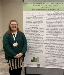 Student Lydia Morgan standing next to a conference poster