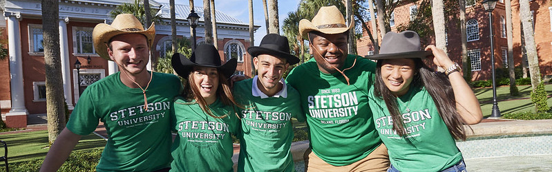 five college students smiling and wearing stetson university shirts and stetson style hats