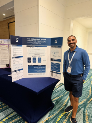 anthony williams standing by a poster and smiling